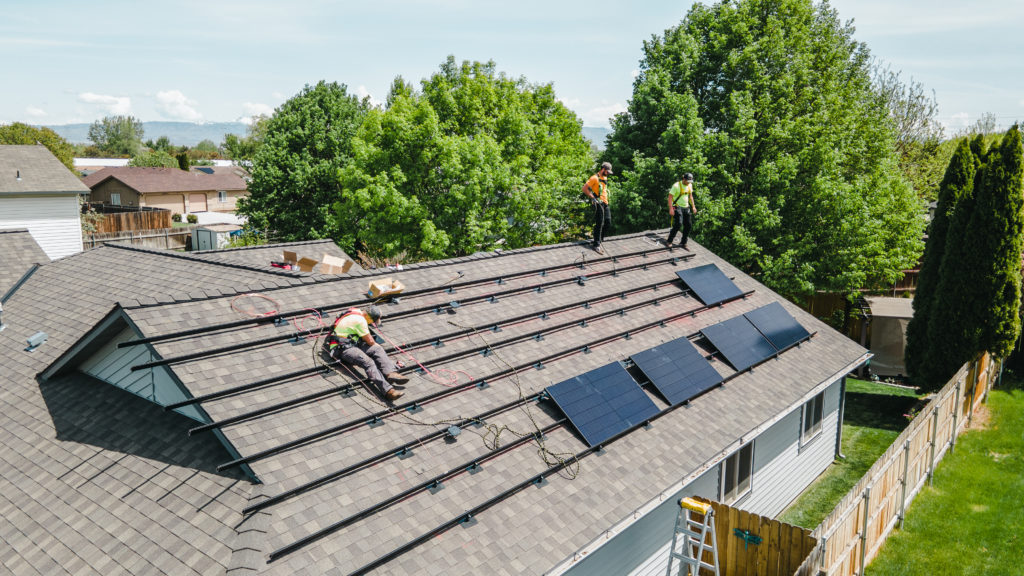 Workers installing solar panels on roof